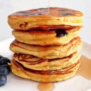 A stack of coconut flour pancakes is topped with maple syrup.