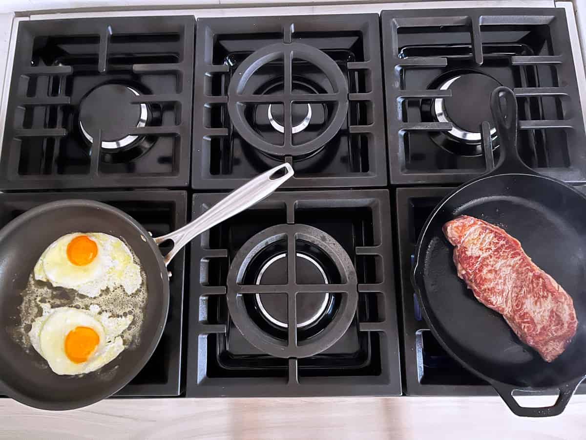 Cooking the steak and the eggs simultaneously.