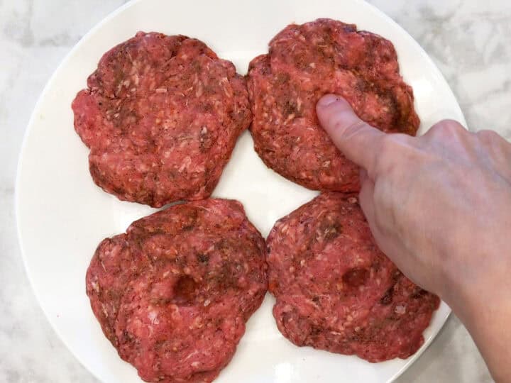 Creating a dimple in the burgers.