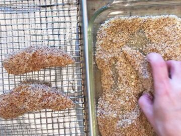 Dredging the chicken in the almond meal-parmesan mixture.