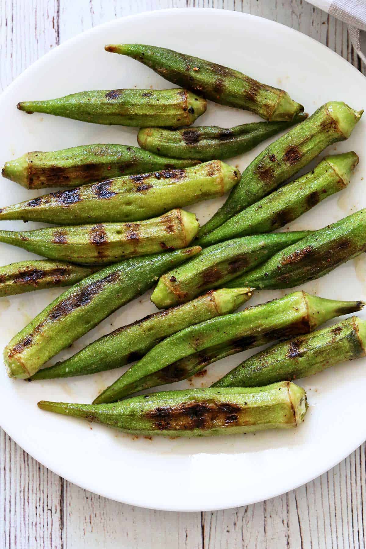 Grilled okra is served on a white plate.