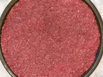 The ground beef covers a pizza pan.