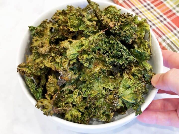 Kale chips are served in a white bowl.