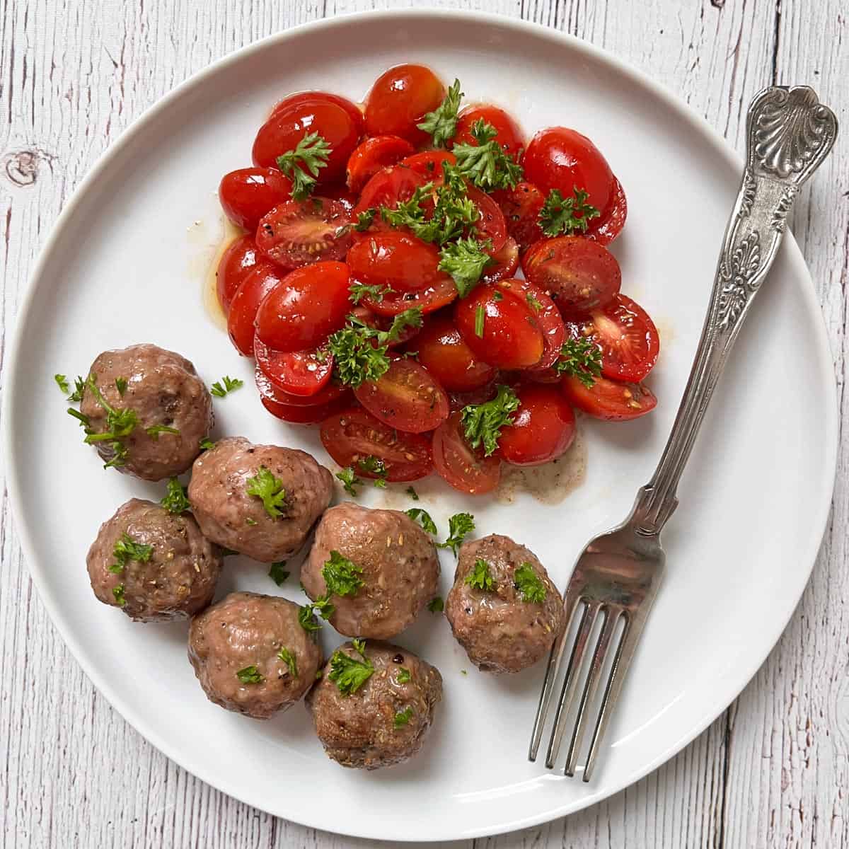 Lamb meatballs (baked version) are served with a cherry tomato salad.
