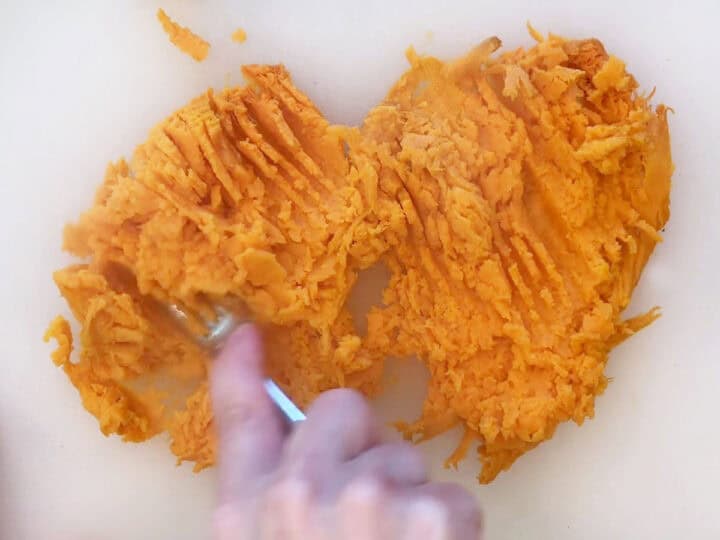 Mashing the sweet potato with a fork.