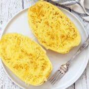 Microwave spaghetti squash on a white plate with a fork.