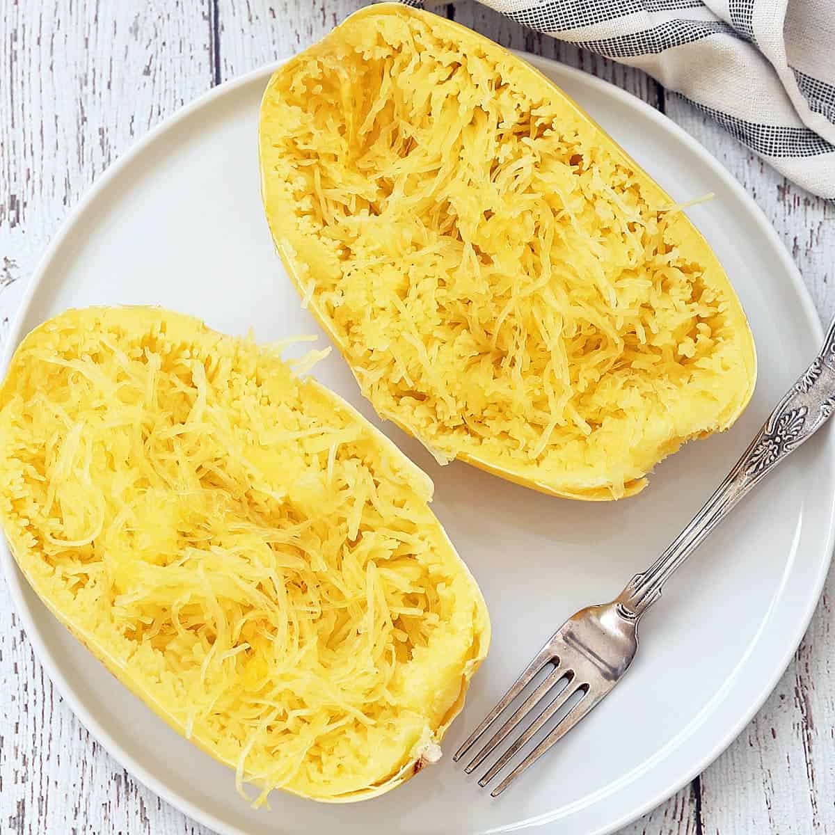 Microwave spaghetti squash on a white plate with a fork.