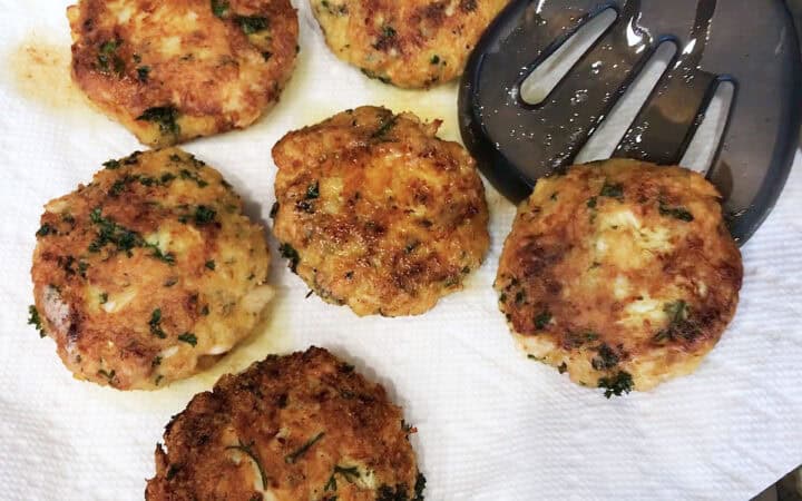 Placing the cooked crab cakes on paper towels.