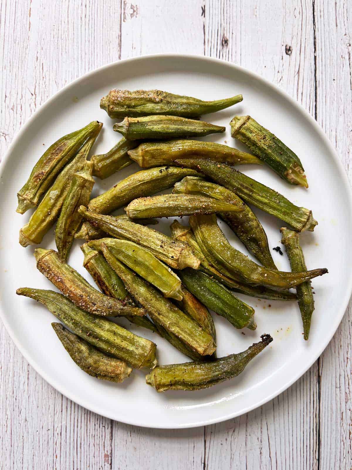 Roasted okra is served on a white plate.