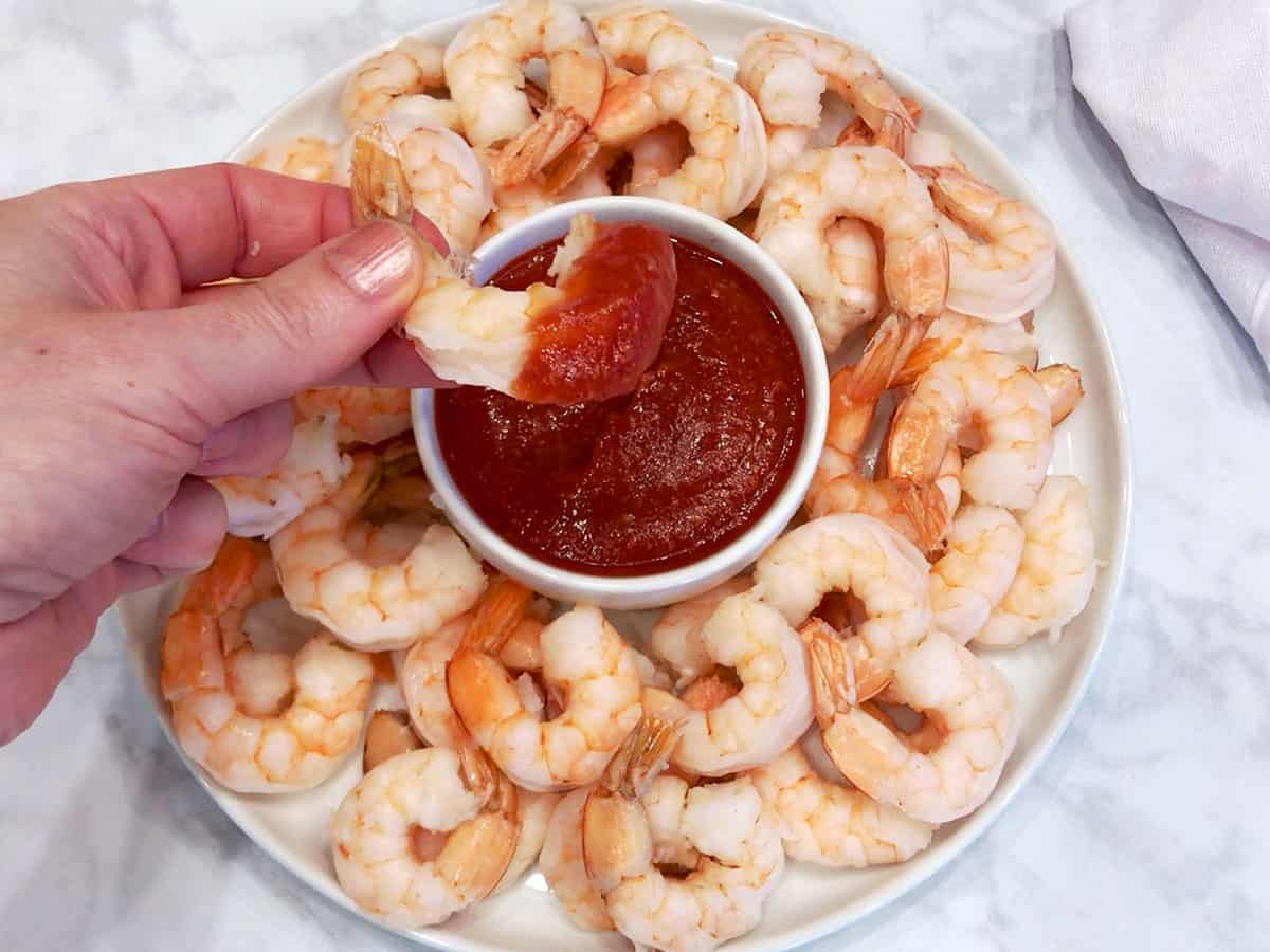 Dipping a shrimp into keto cocktail sauce.