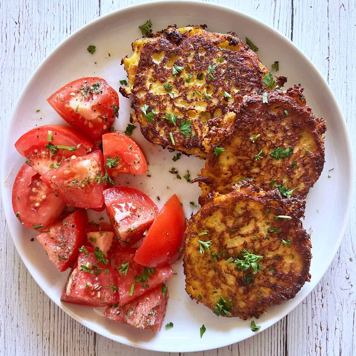 Spaghetti squash fritters are served with a tomato salad.