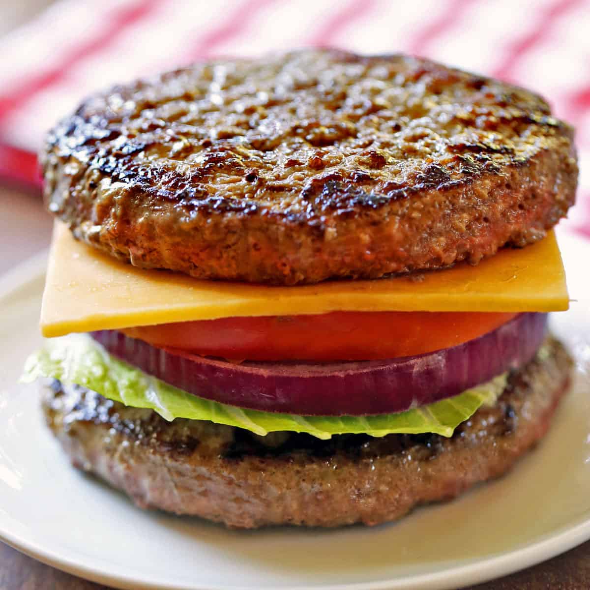 A bunless burger is served on a white plate.