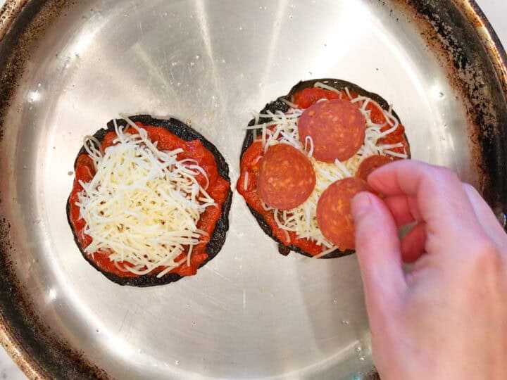 Adding toppings to the mushrooms.