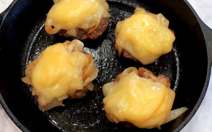 The burgers were topped with onions and melted cheese.