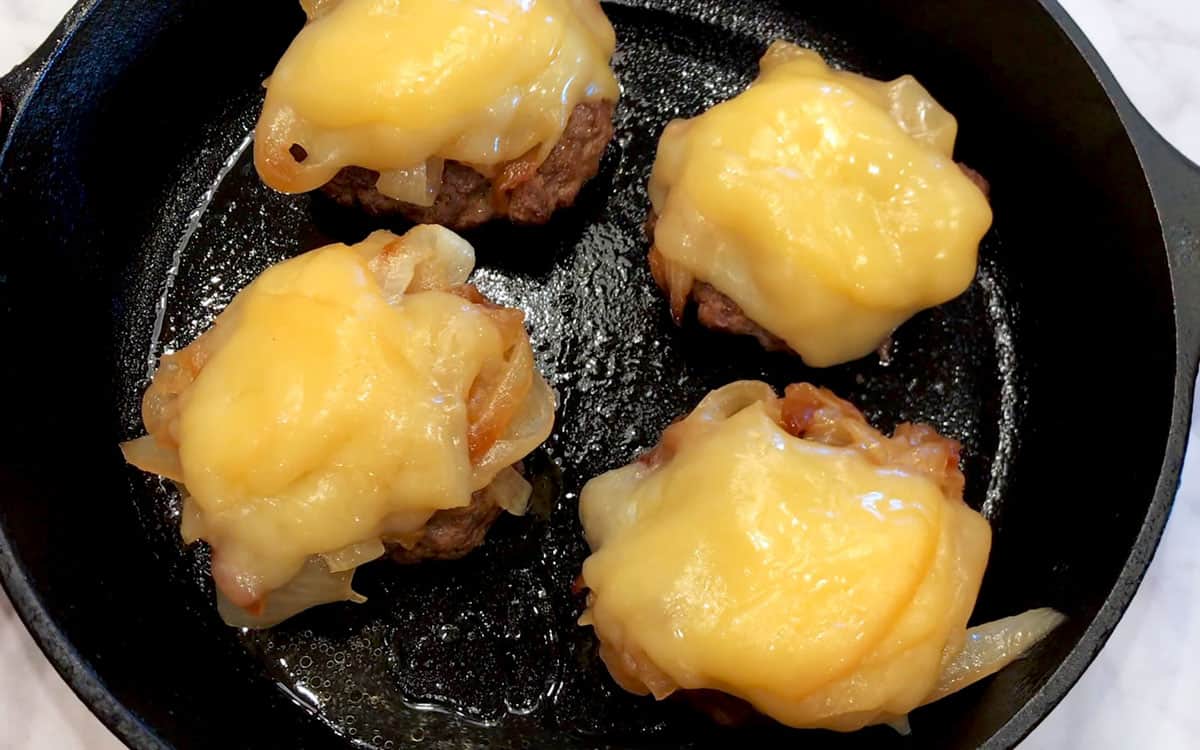 The burgers were topped with onions and melted cheese.