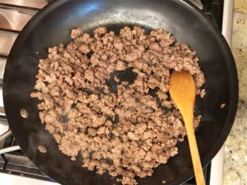 Cooking the ground beef in a skillet.