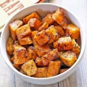 Roasted butternut squash is served in a white bowl.