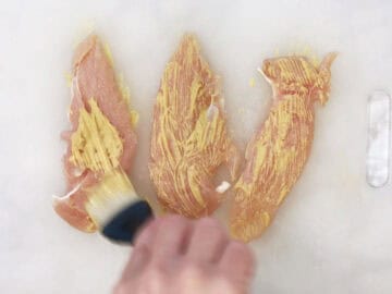 Coating the tenders in mustard.