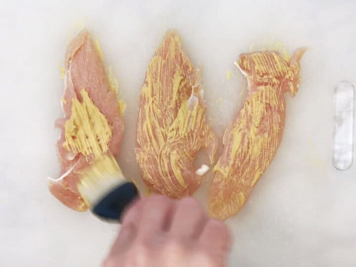 Coating the tenders in mustard.