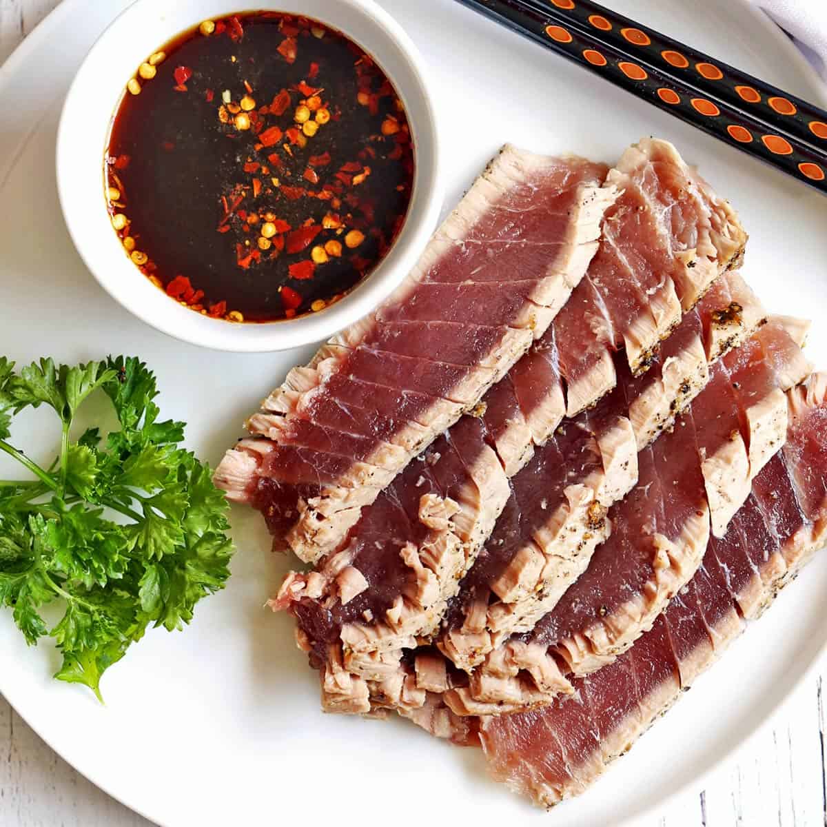 Seared tuna steak is served with a dipping sauce.