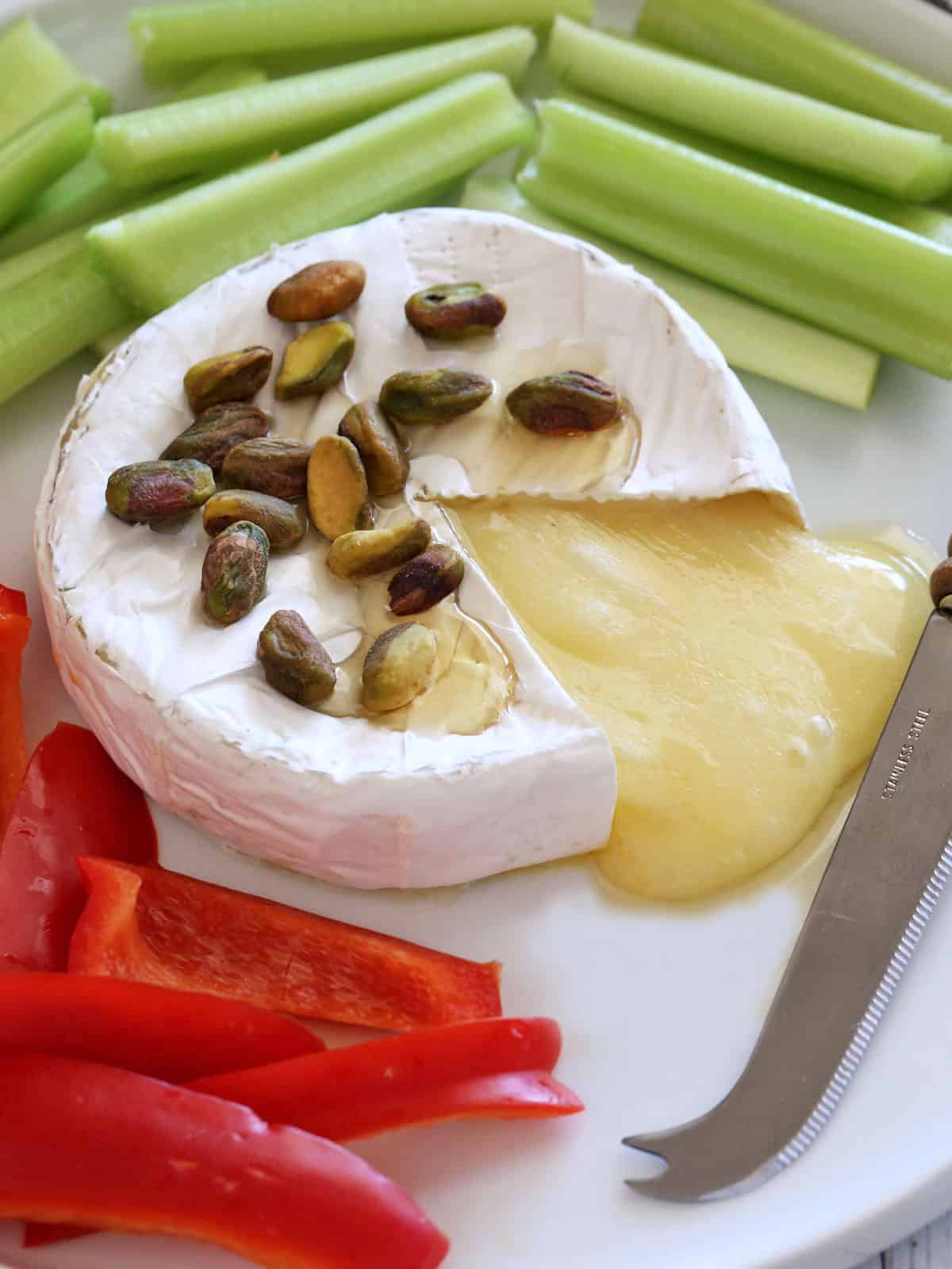 Baked brie is served with vegetables.