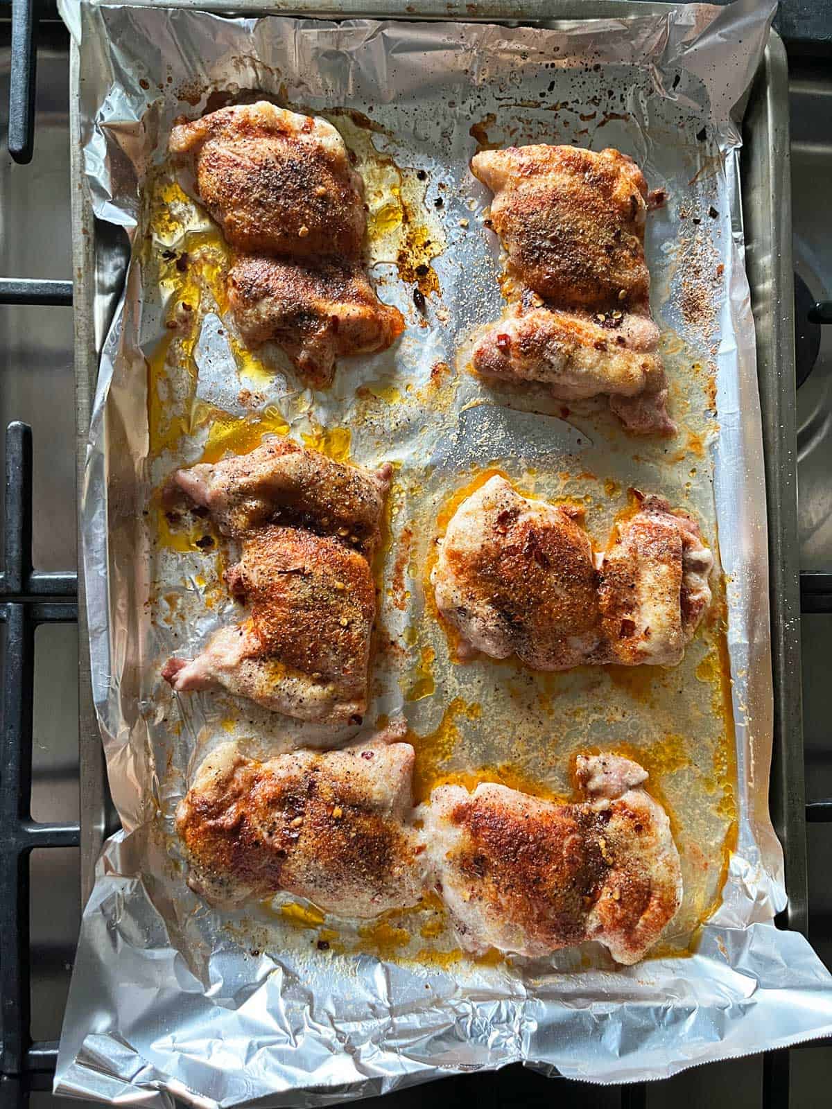 Boneless chicken thighs on a foil-lined baking sheet.