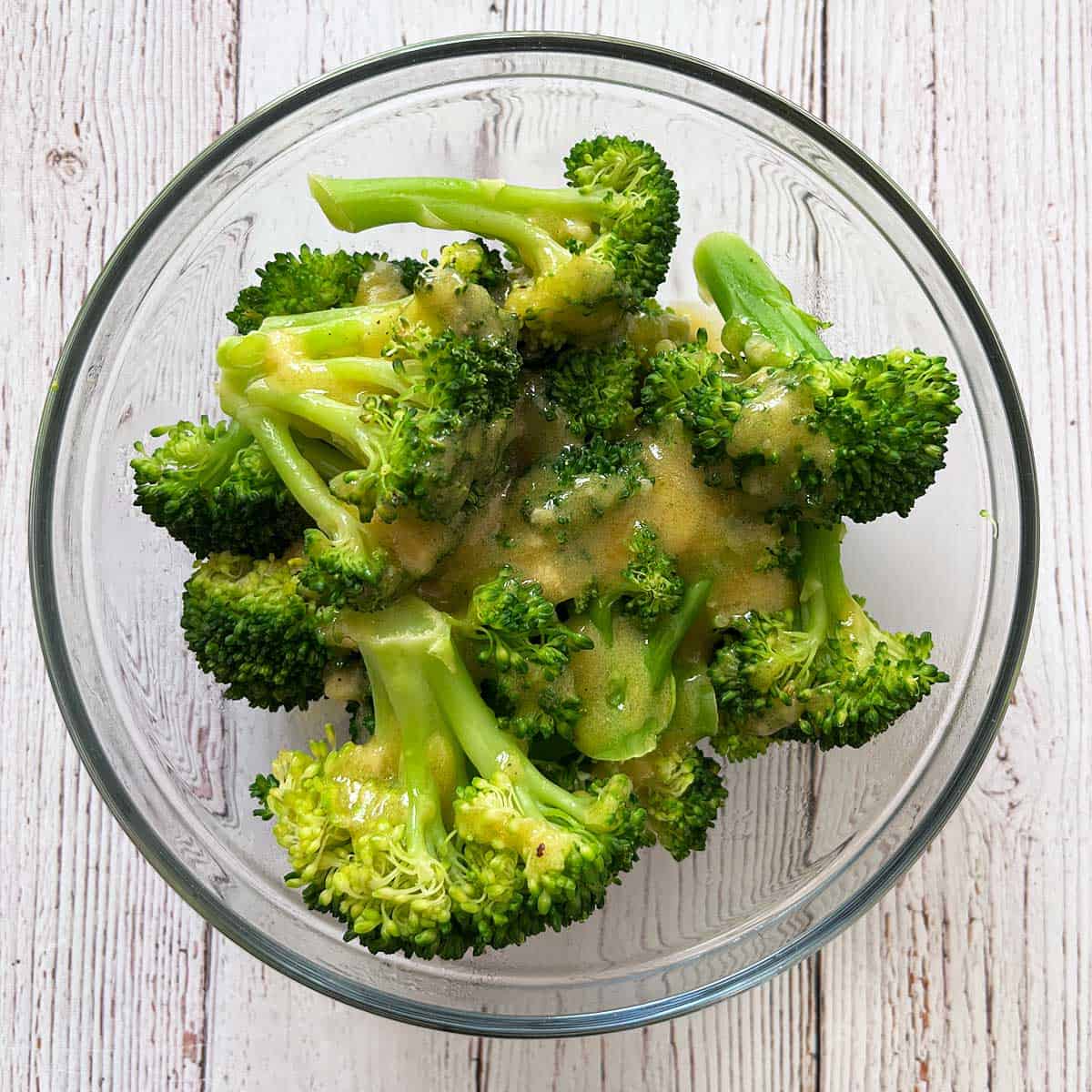 Steamed broccoli is topped with vinaigrette.