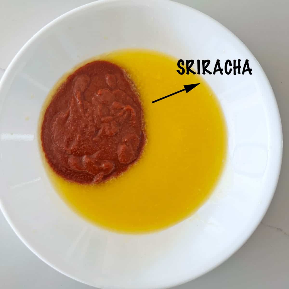 Adding sriracha to the melted butter.