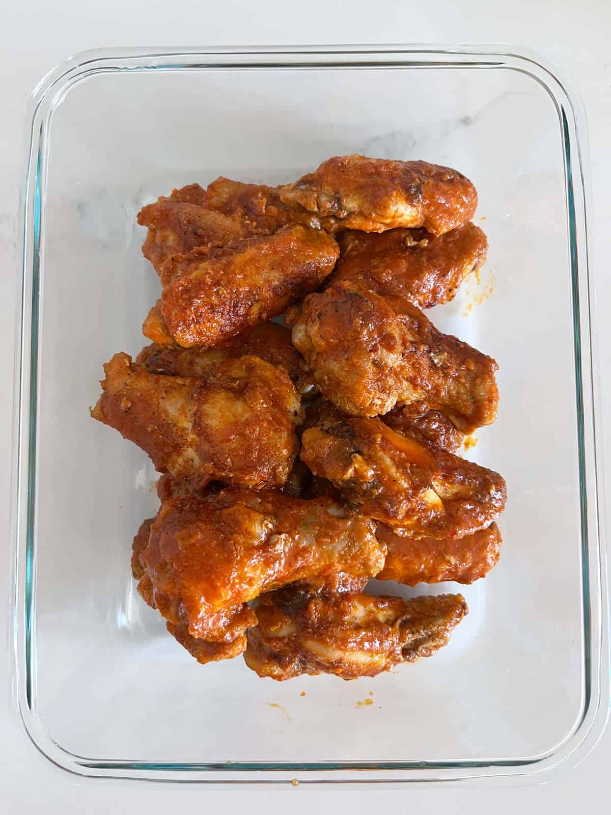 Leftover wings are kept in a glass food storage container.