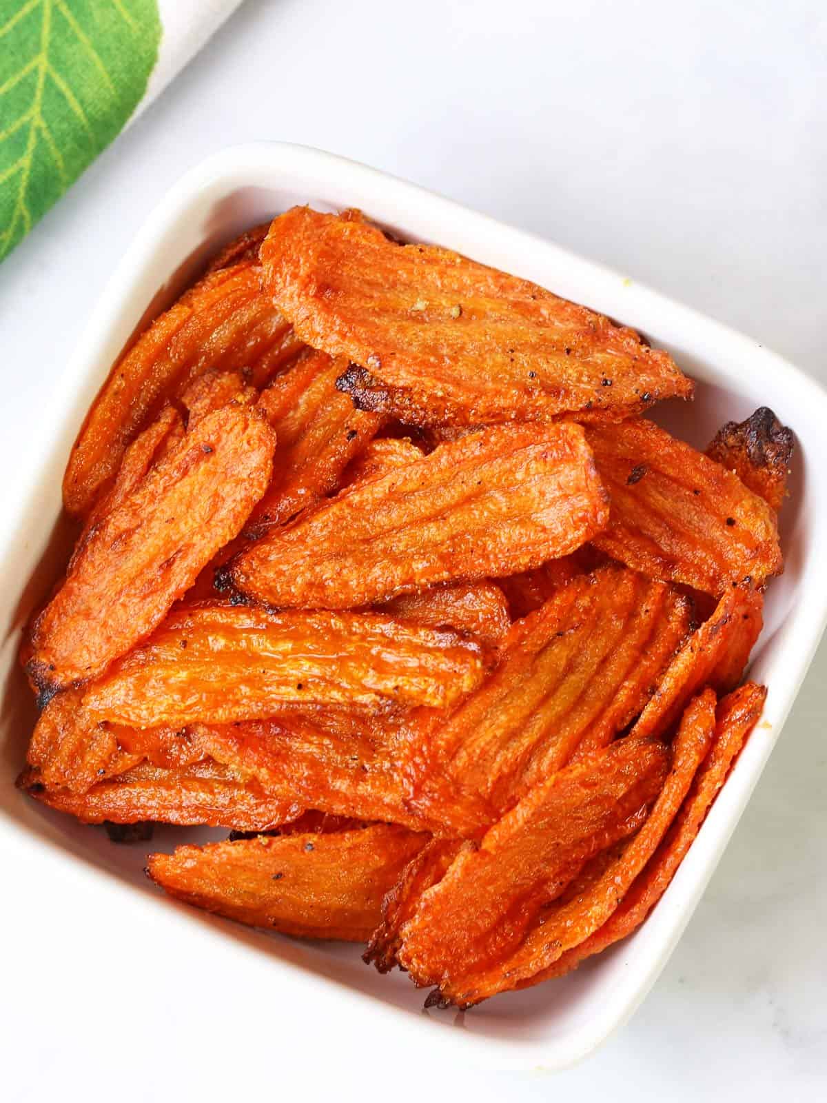 Carrot chips are served in a white bowl.