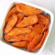 Carrot chips are served in a white bowl.