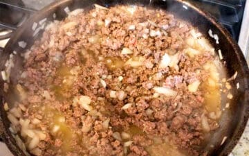 Cooking ground beef and onions in a skillet.