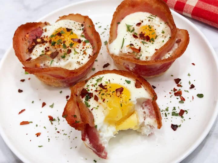 Three bacon egg cups on a plate, one of them was bitten.