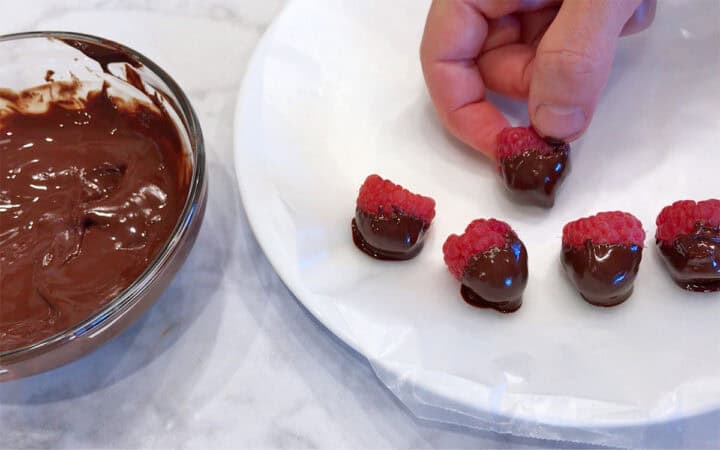 Dipping the raspberries in the melted chocolate.