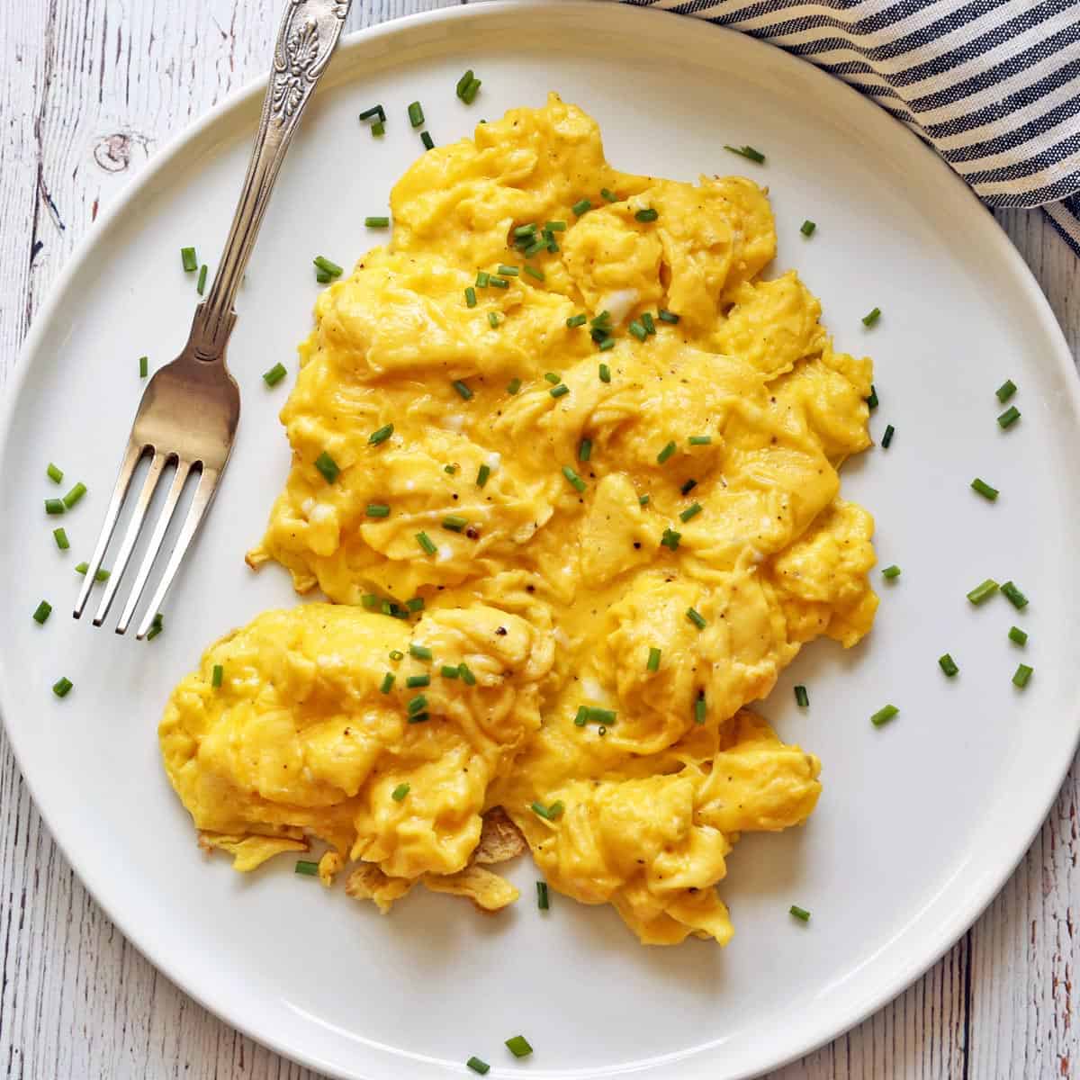 Fluffy scrambled eggs are served with a fork.