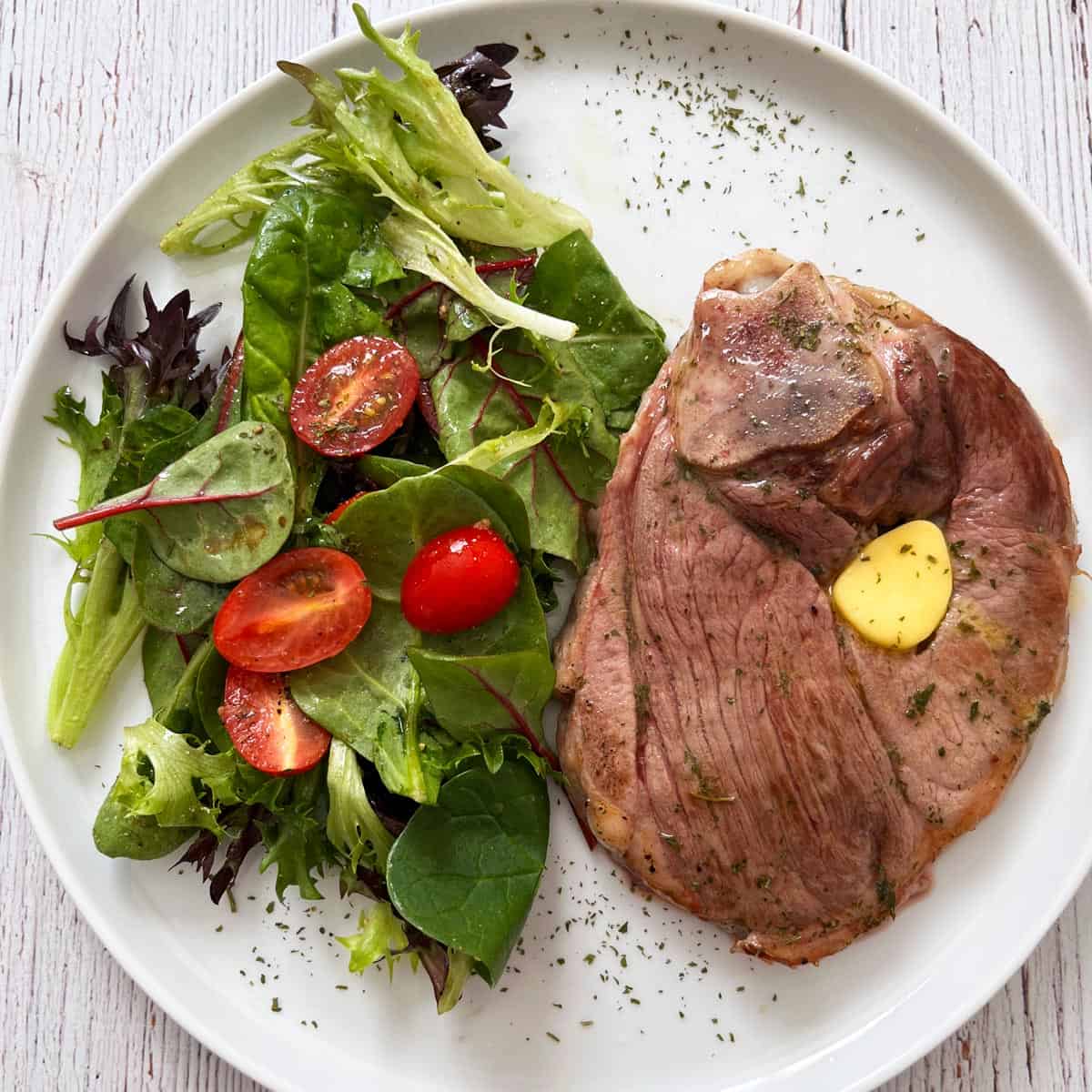 Lamb steak is served with a salad.