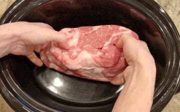 Placing the pork in the slow cooker.