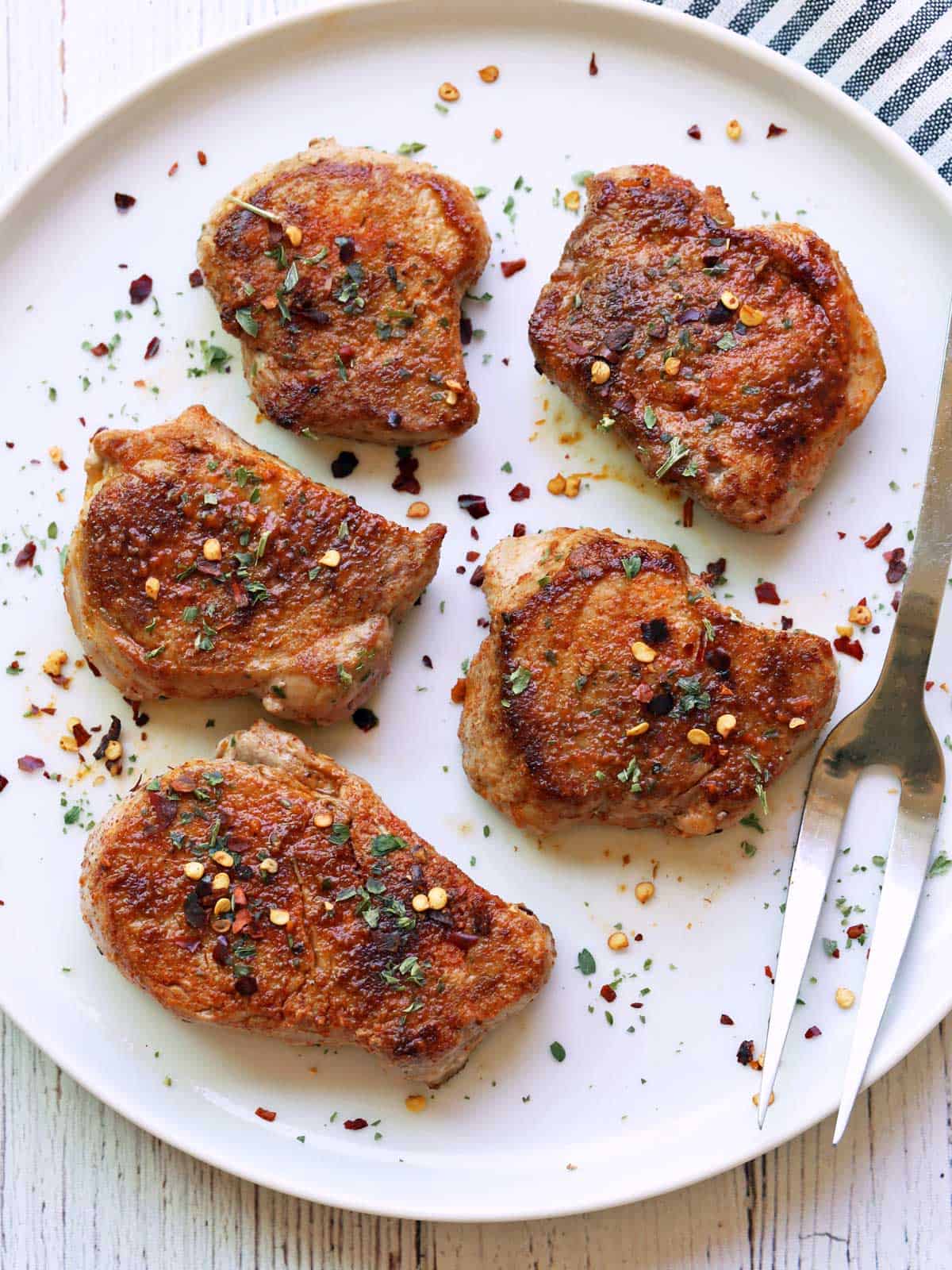 Pork medallions are served on a white plate with a serving fork.