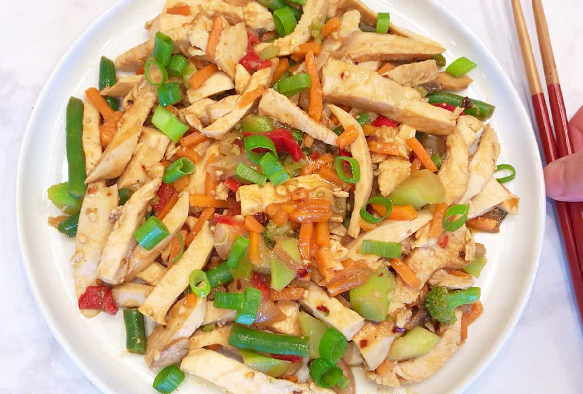 The stir fry is served with chopsticks.