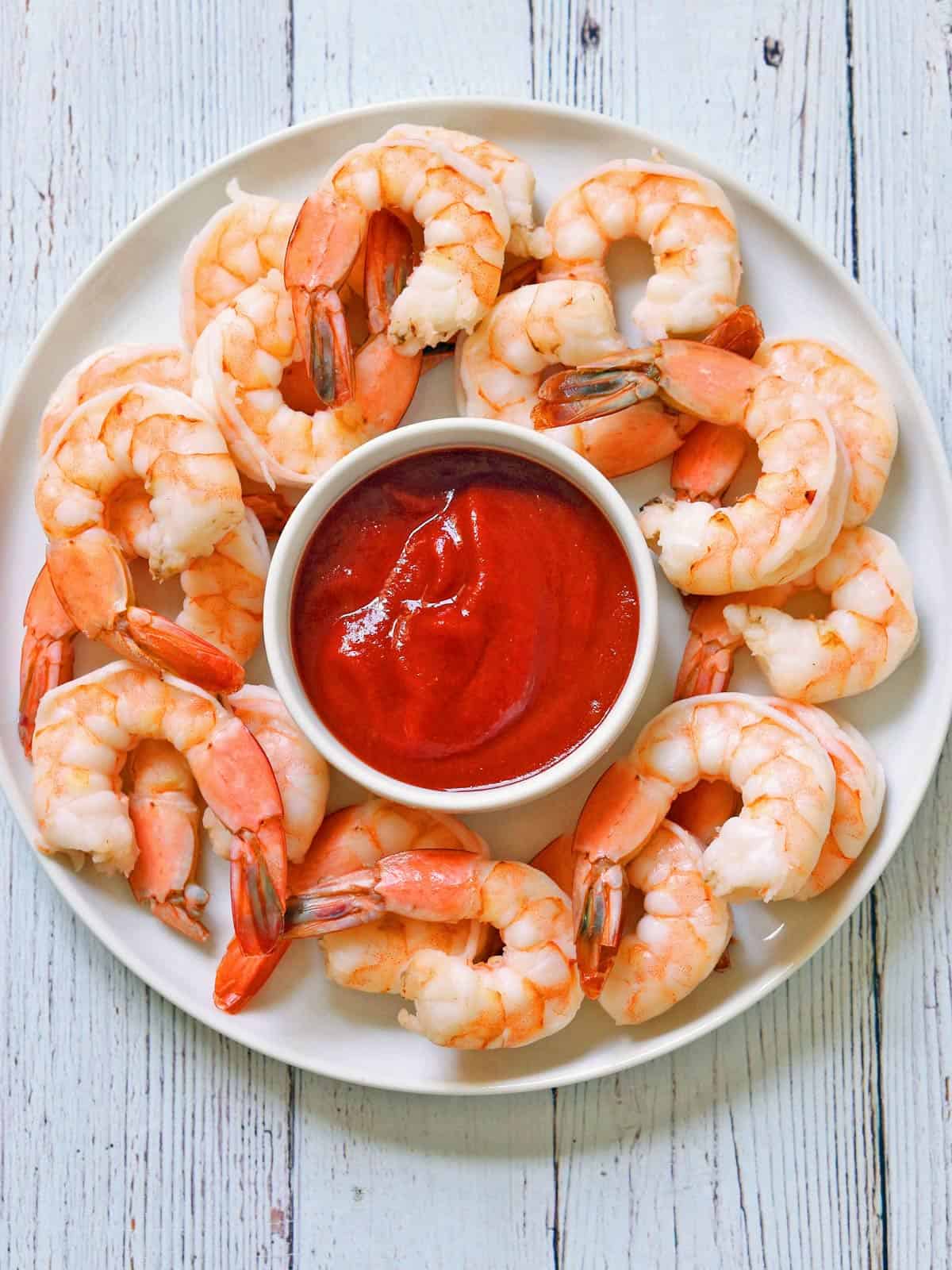 Boiled shrimp are served with cocktail sauce.