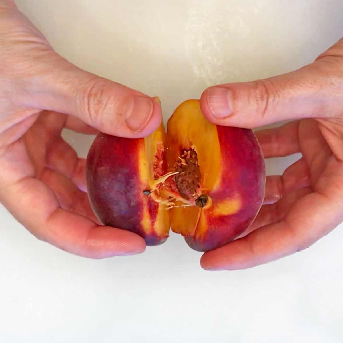 Pulling the two peach halves apart.