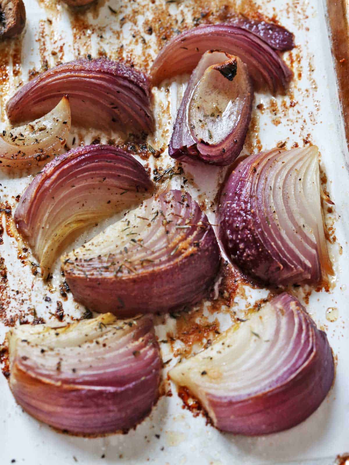 Red onion wedges on a parchment-lined baking sheet.