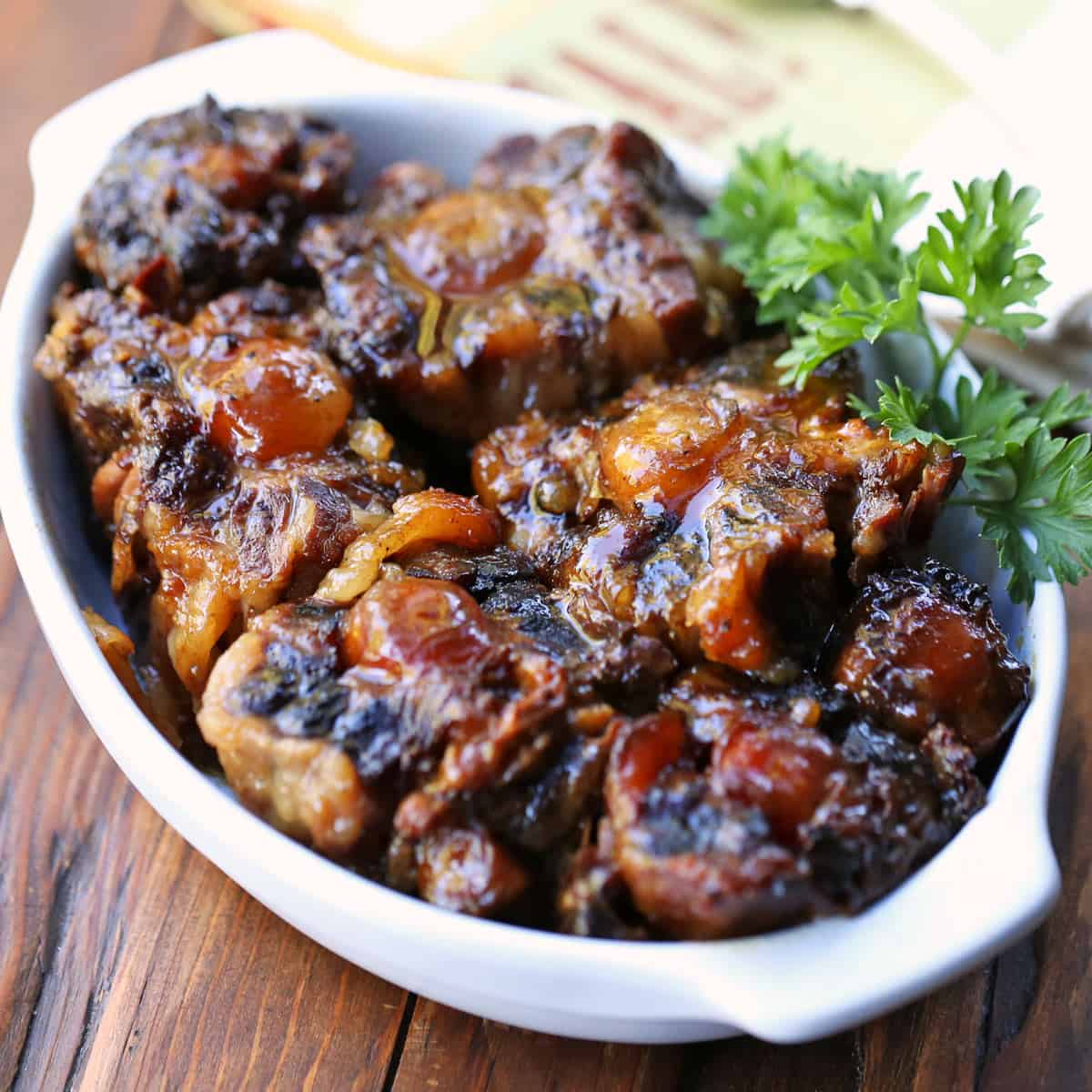 Slow cooker oxtail is served in a white dish.