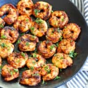 Spicy shrimp are served on a black plate.