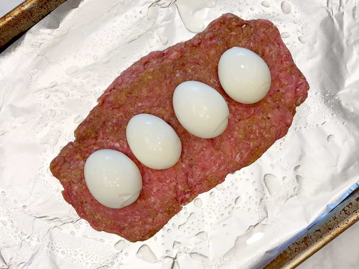 Topping the bottom beef layer with hard-boiled eggs.