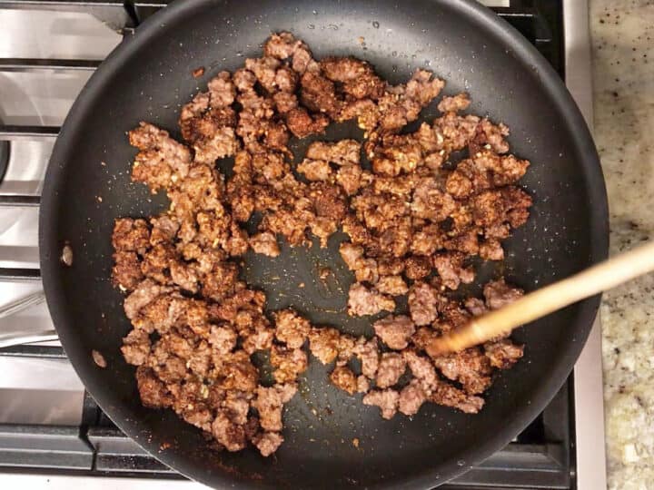 Adding garlic and spices to the ground beef.