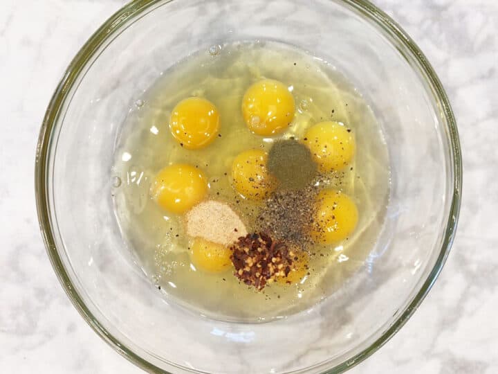 Mixing eggs and spices in a bowl.