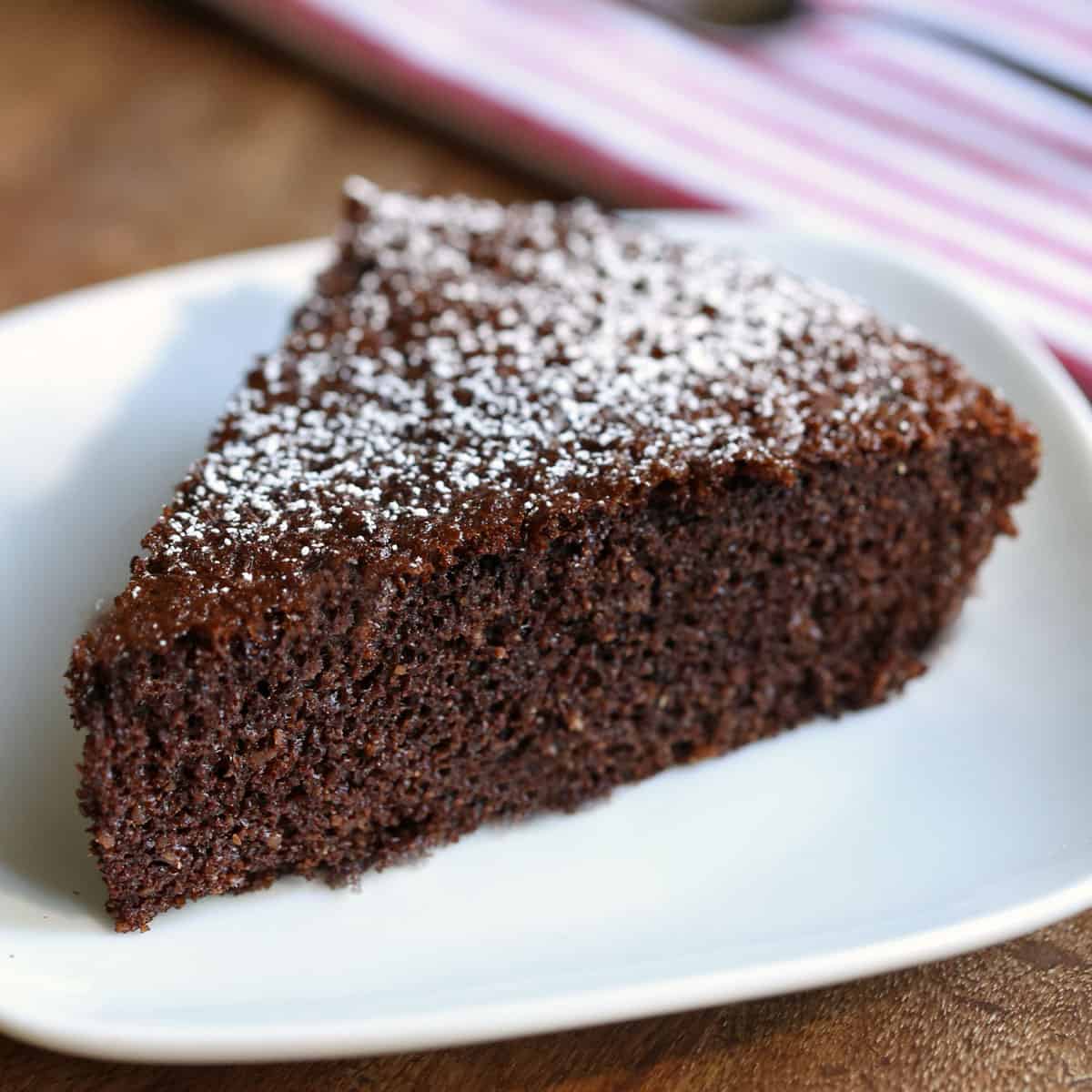 A slice of almond flour chocolate cake shows its moist, tender crumb.