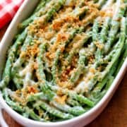 Keto green bean casserole is served in a white baking dish with a red napkin in the background.
