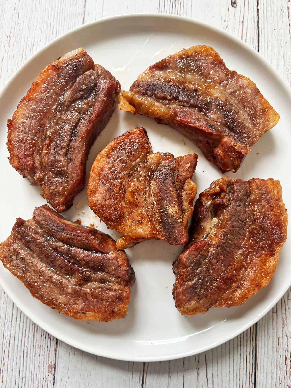 Pork belly strips are served on a plate.